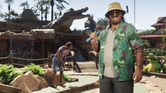Cal Hampton grinning with a putter over his shoulder on a jungle-themed mini golf course with alligator statues, as another player putts behind him.