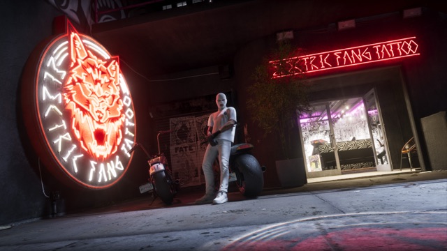 The Electric Fang Tattoo parlor at night: a round neon wolf sign and a red neon name sign over the open door, with a person in a white balaclava leaning on a motorcycle.