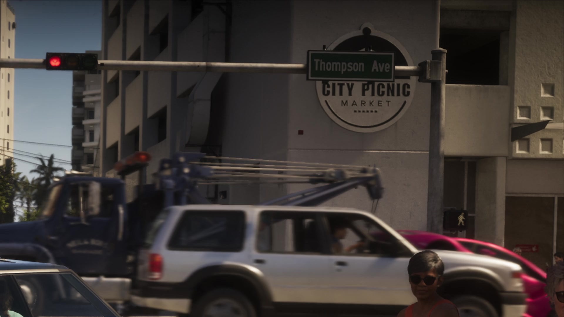 A round City Picnic Market sign on a white building behind a Thompson Ave street sign and passing traffic.