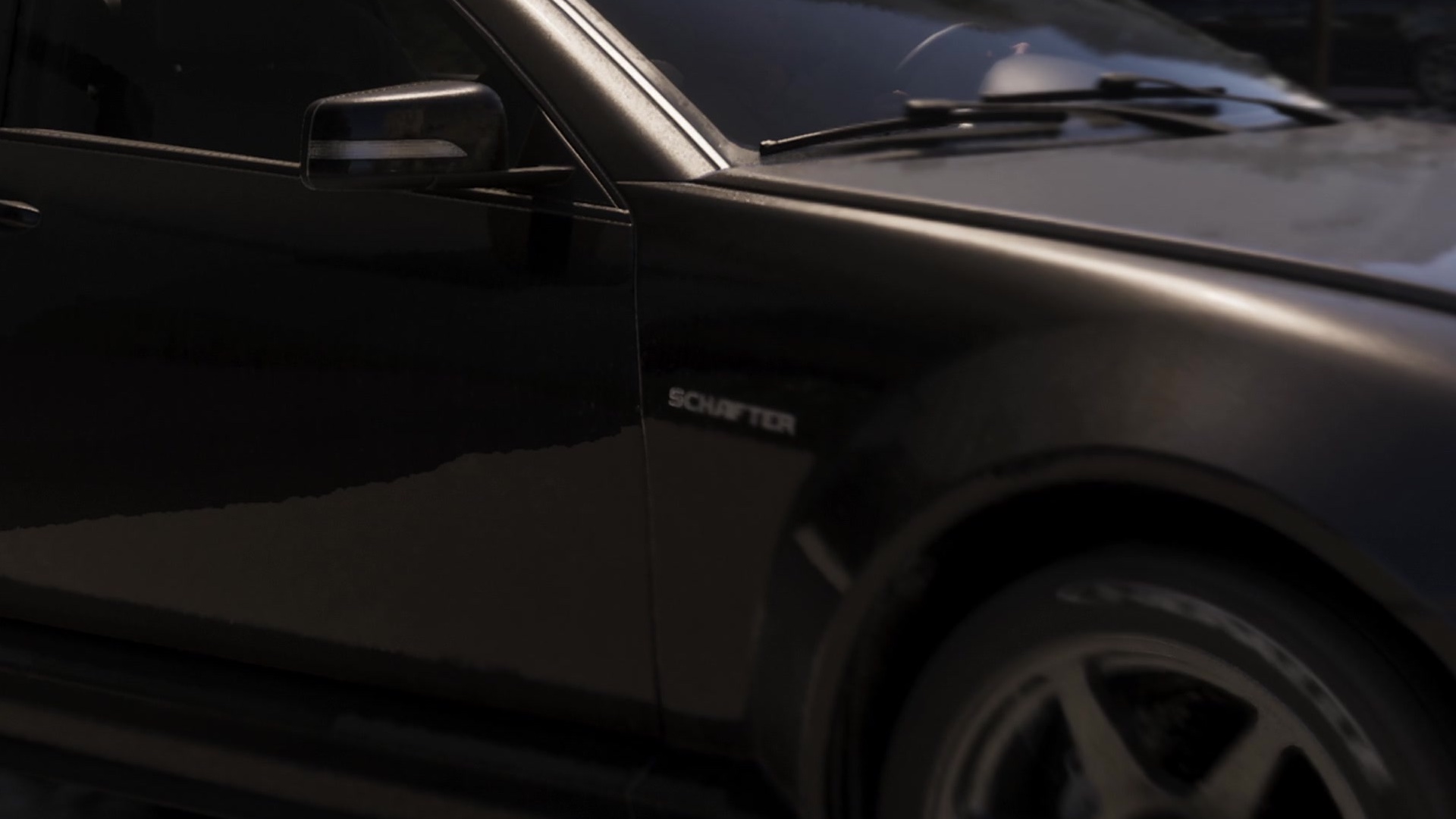 The front fender of a dark car with a chrome Schafter badge.