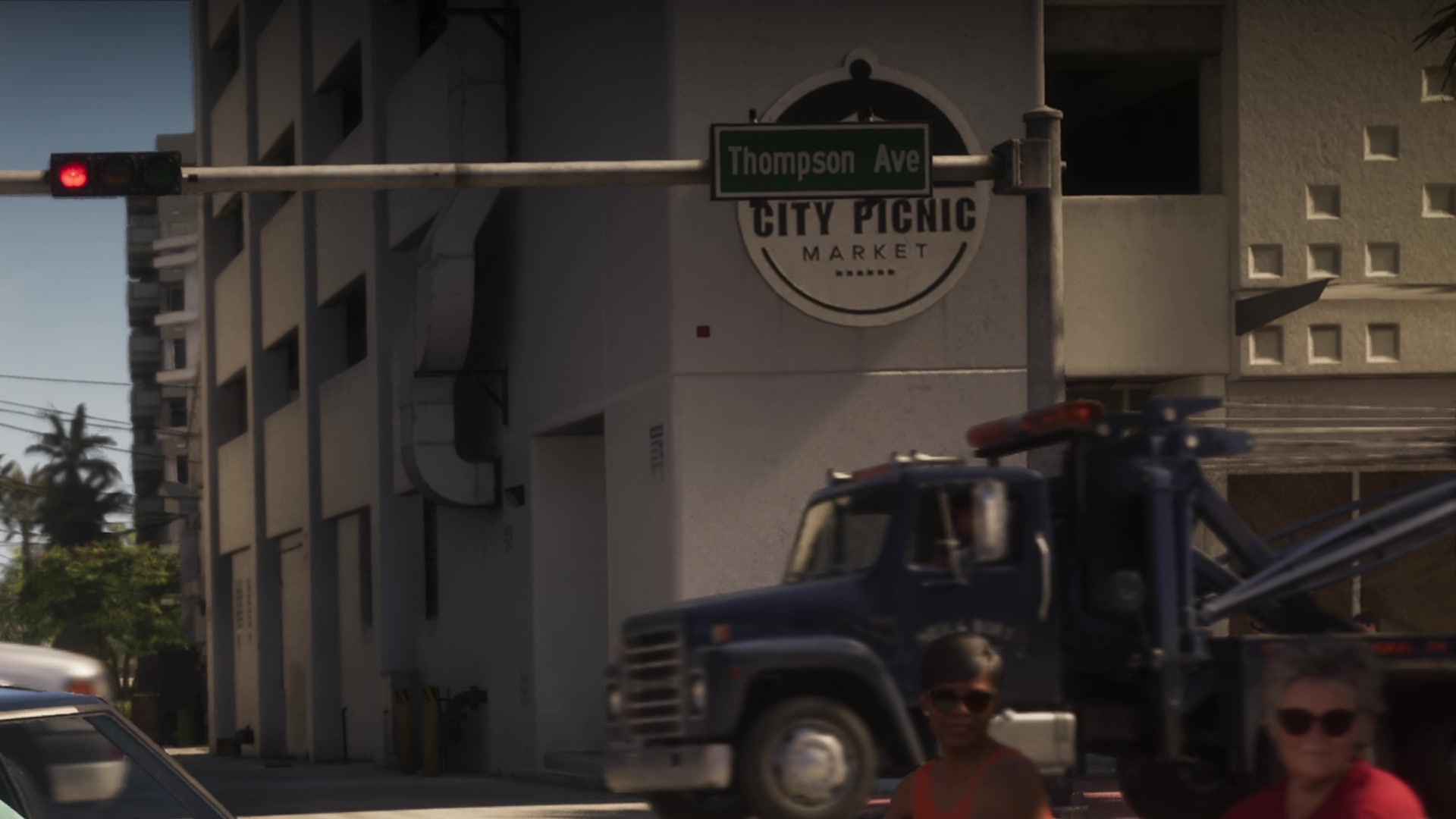 A Thompson Ave street sign at a traffic light in front of a City Picnic Market sign, a tow truck below.
