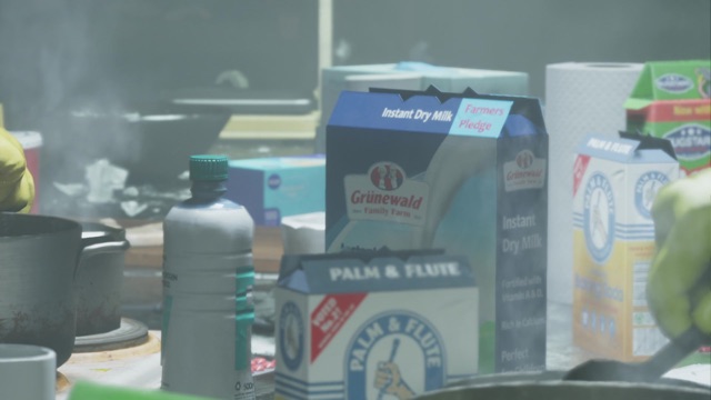 A cluttered counter with a Grünewald Family Farm instant dry milk carton and a Palm and Flute box.