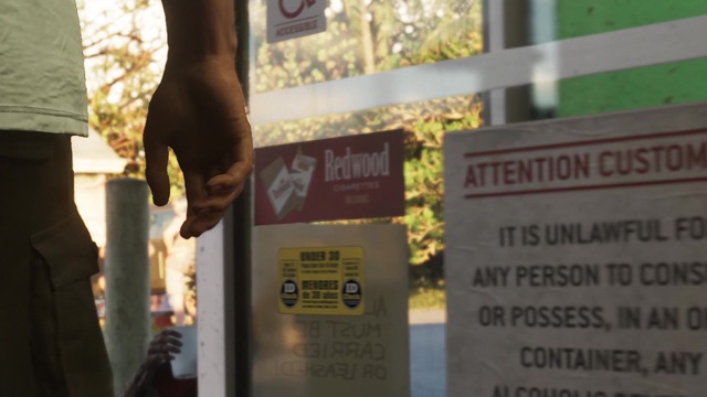 A Redwood Cigarettes sign and a notice for customers at a store entrance, a man's arm in the foreground.